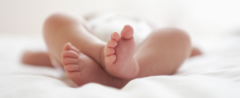 Newborn baby laying on back with feet up.