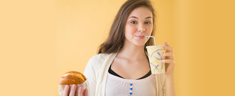 Girl eating a sandwich and a drink.